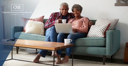 African American older couple sitting on a couch looking at a laptop
