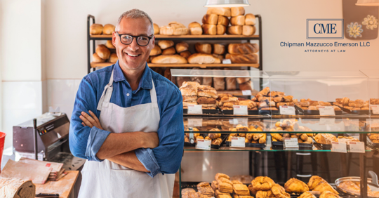 Bakery business owner stands in front of display of bread
