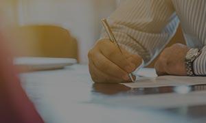a man writing down on a paper